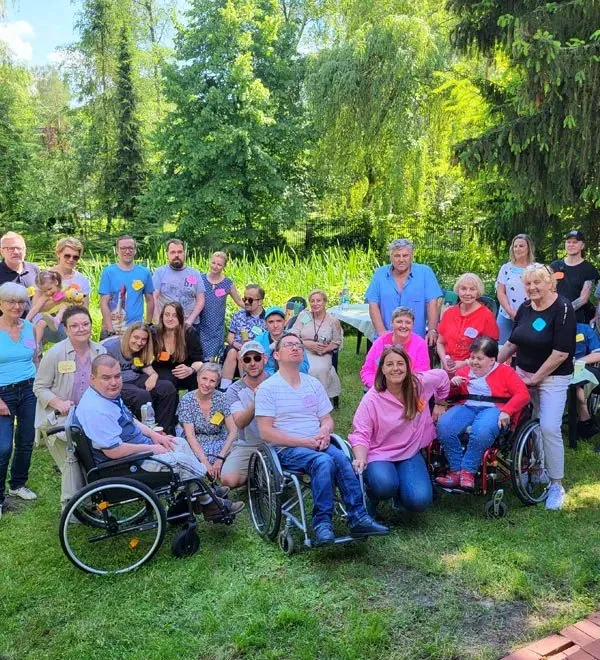 Grupa osób, część na wózkach, na trawniku